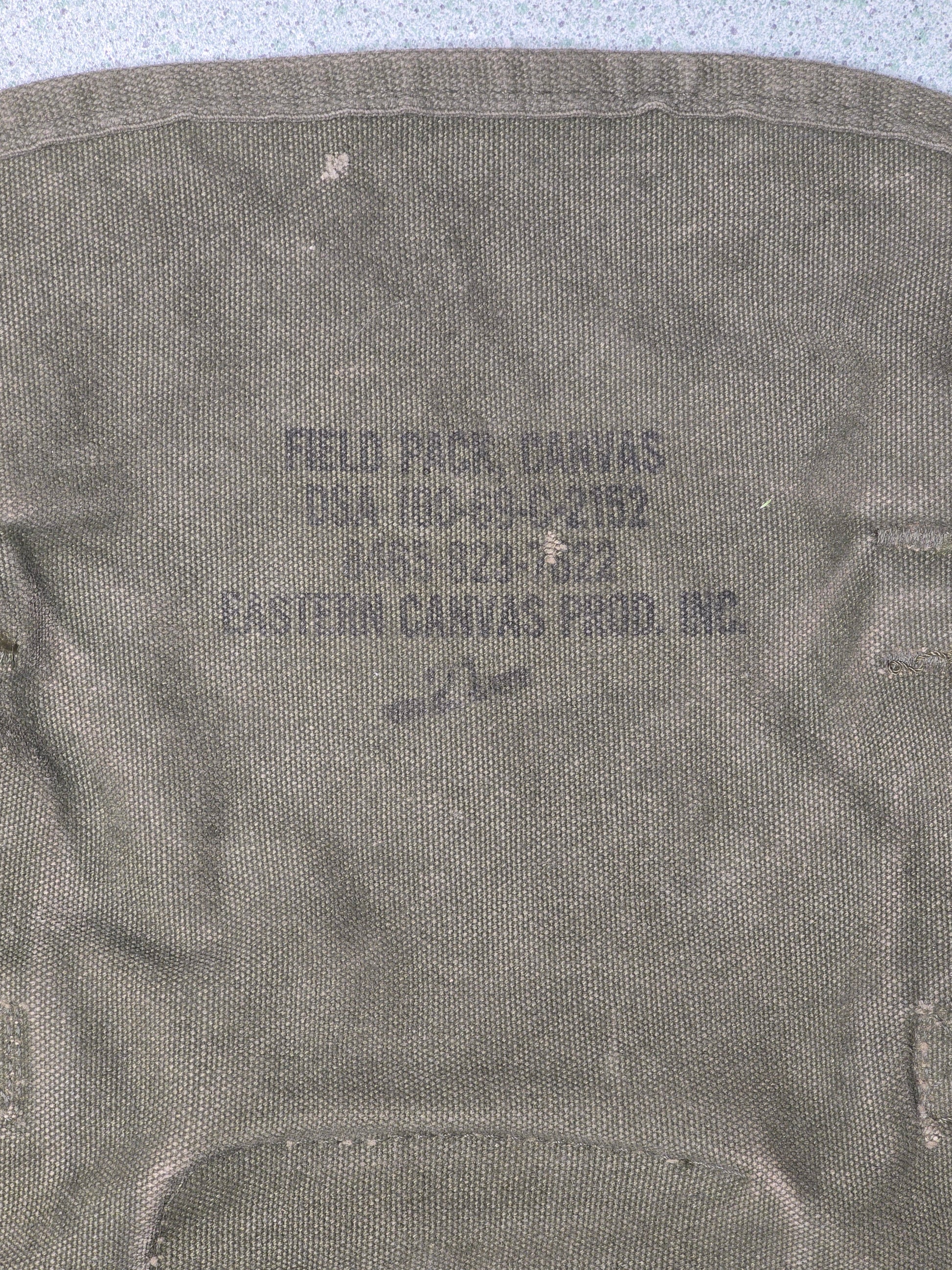 U.S. M-1961 Vietnam War "Field Pack Canvas" Bags Vintage military backpack on a gray background 
,Gray fabric with printed text on a light gray background